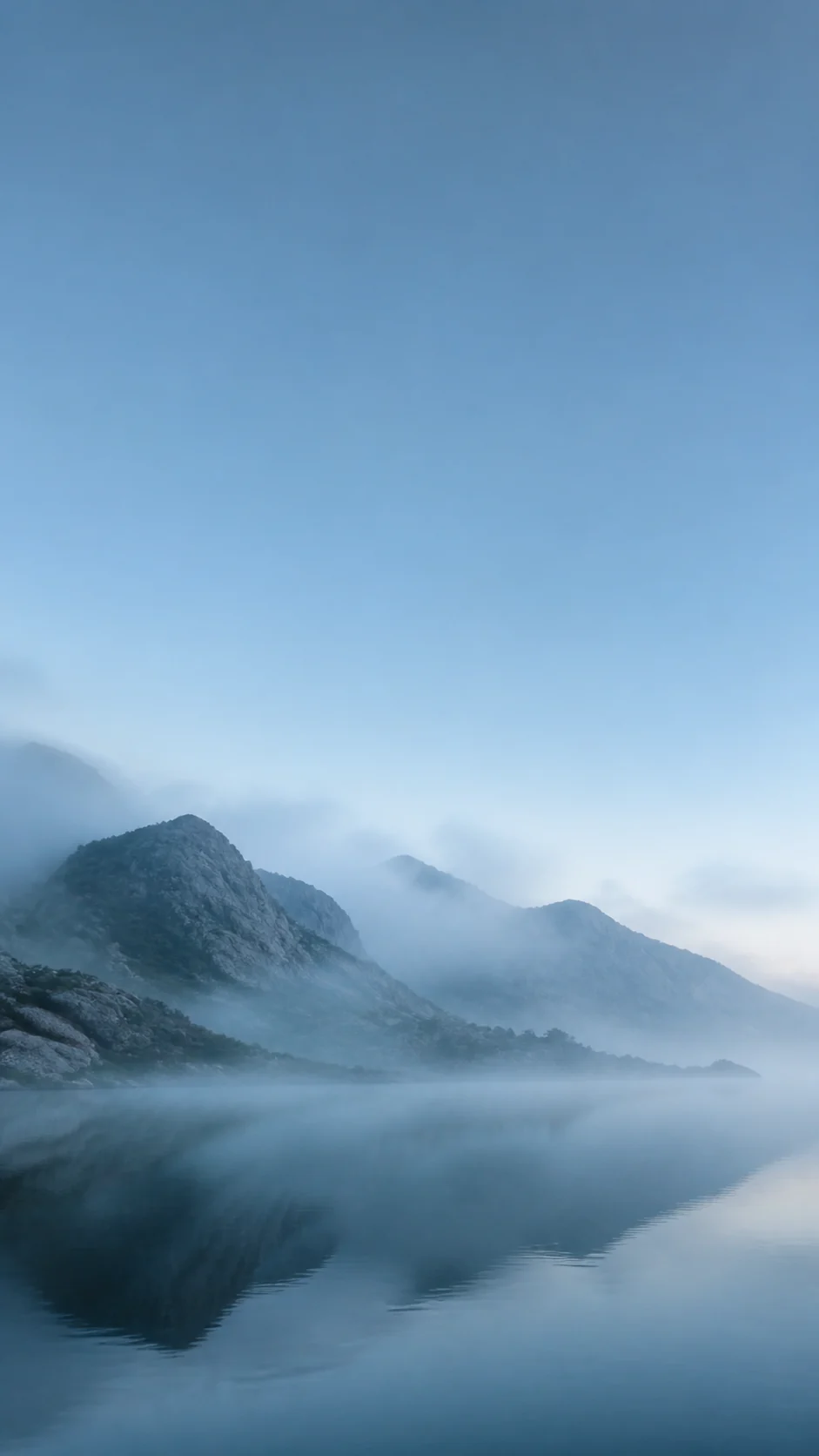 清晨雾岭与玻璃湖面的冷青色竖屏手机壁纸,顶部为锁屏留白